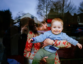 Grandmother holding smiling toddler boy in floral sweater