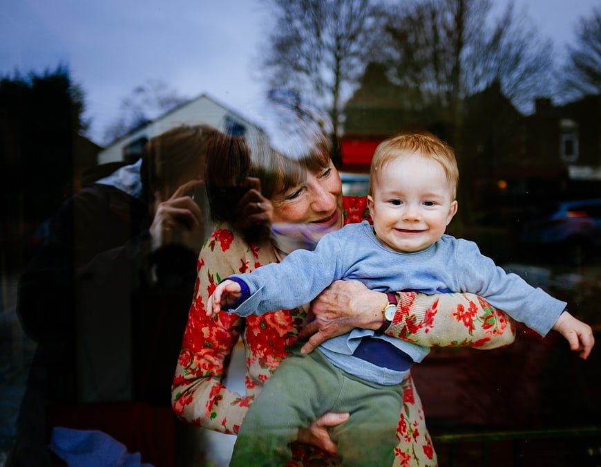 Grandmother holding smiling toddler boy in floral sweater
