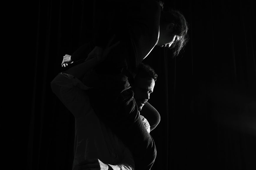 Dramatic black and white silhouette of dancers performing a lift