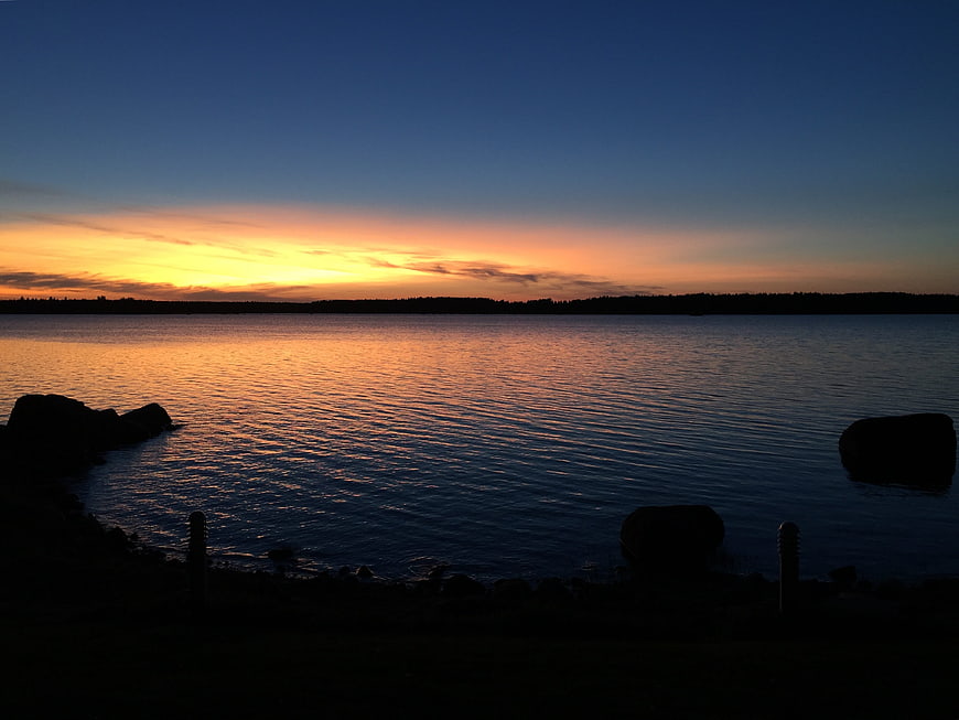 Serene Sunset Over Calm Lake with Silhouetted Rocks