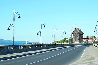 Empty coastal road with historic wooden windmill and sea view