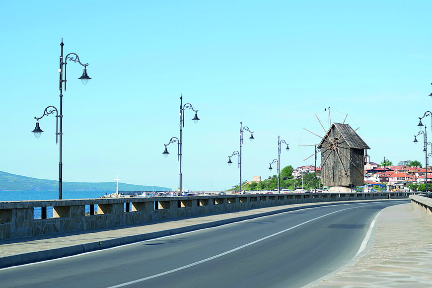 Empty coastal road with historic wooden windmill and sea view