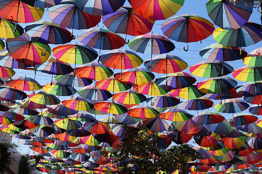 Colorful rainbow umbrellas hanging against blue sky