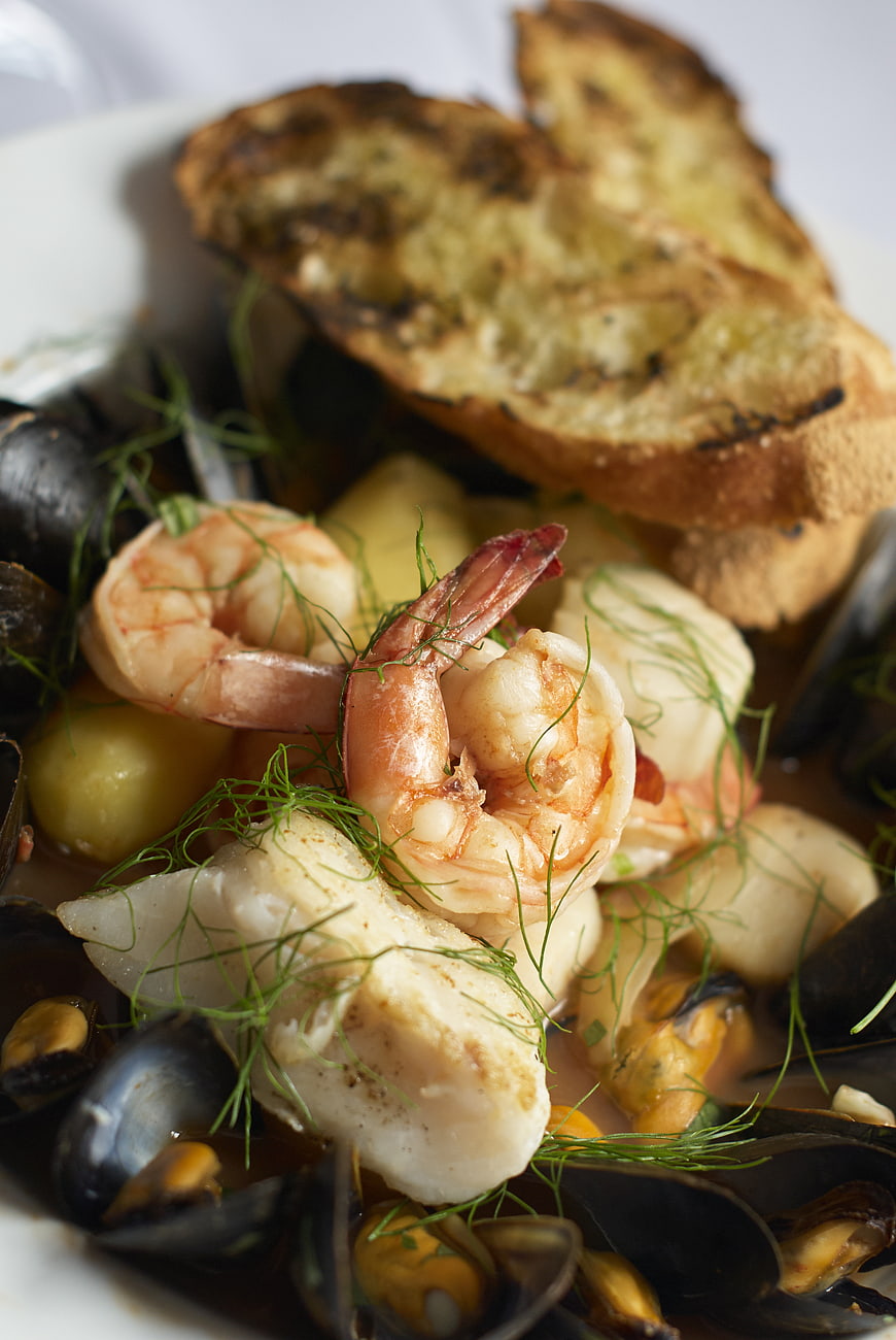 Close-up of gourmet seafood stew with shrimp, mussels, and garlic bread