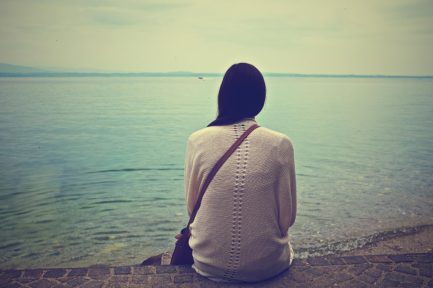 Woman Sitting by Lake Looking at Horizon