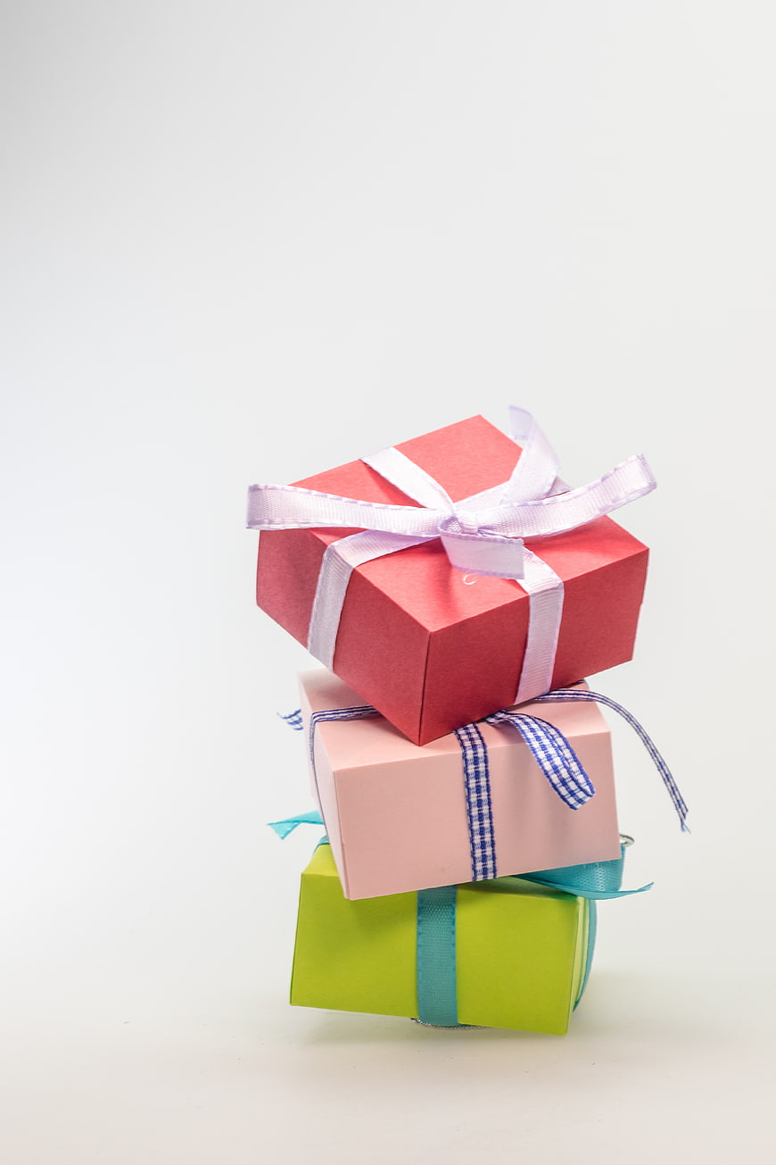 Stack of colorful gift boxes with ribbons on white background