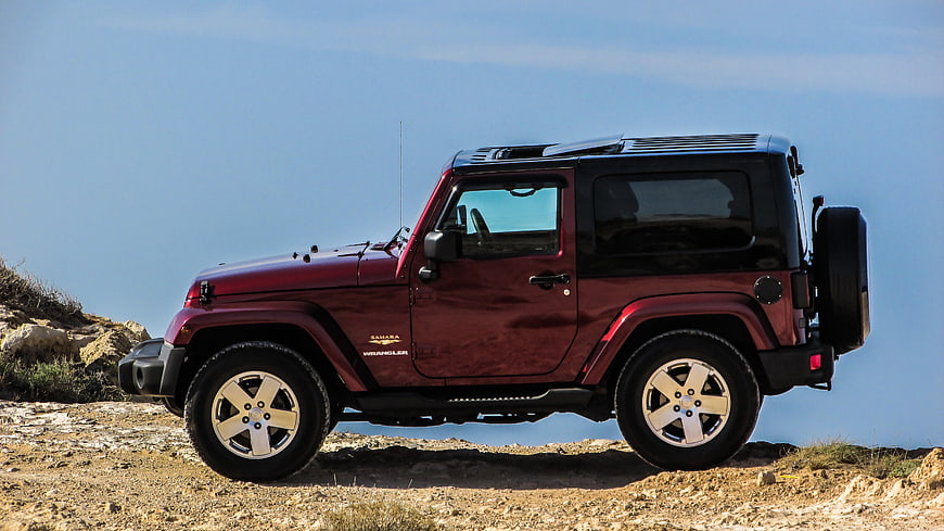 Side Profile Of Maroon Jeep Wrangler On Rocky Terrain