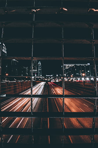 Night city traffic light trails through metal grid