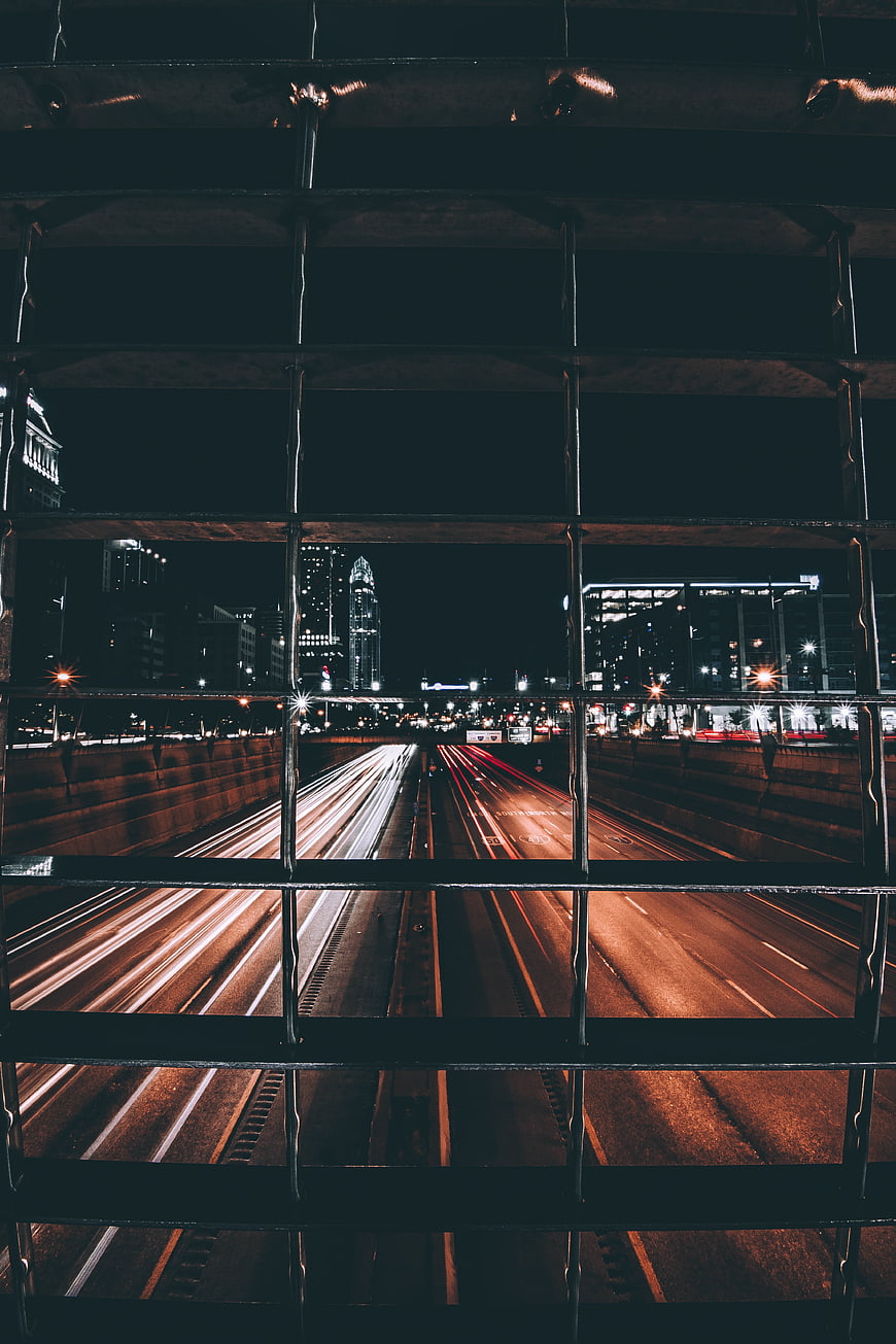 Night city traffic light trails through metal grid