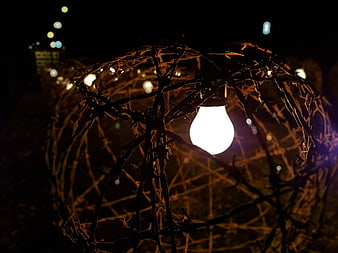 Light bulb inside barbed wire sphere at night