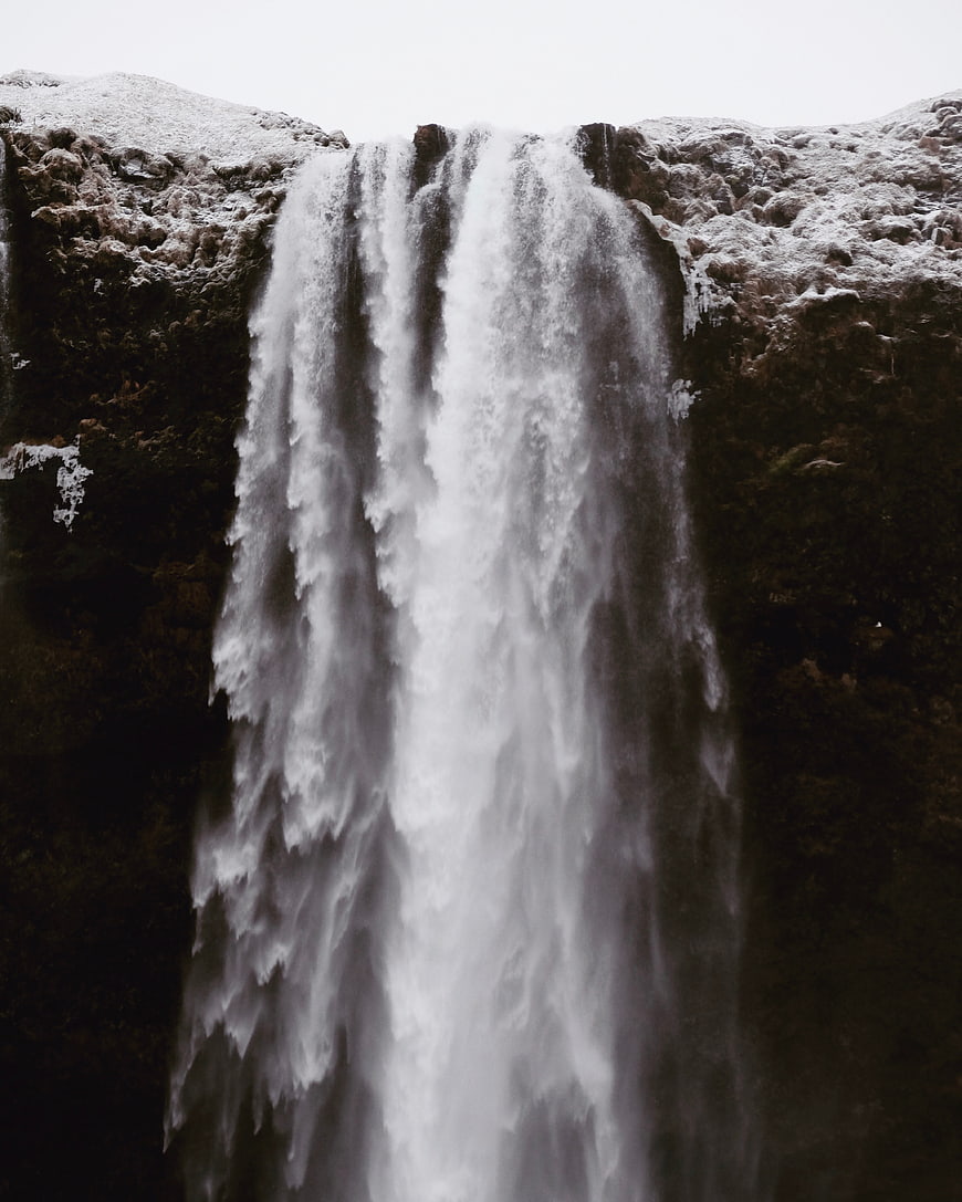 Majestic waterfall cascading down dark rocky cliff in winter