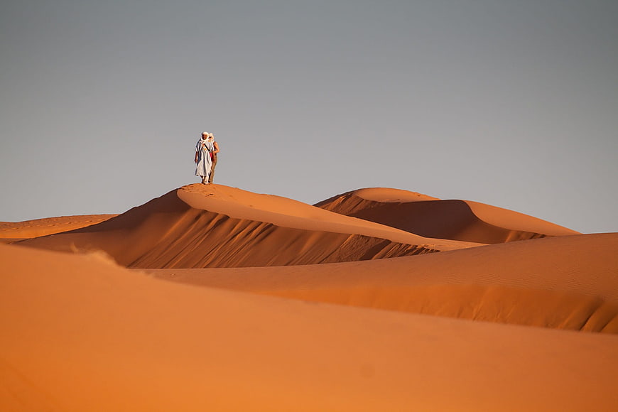 Couple Walking on Red Sand Dunes in Moroccan Desert