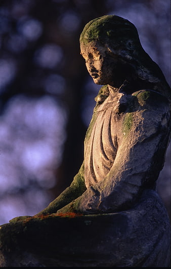 Weathered Stone Statue in Cemetery at Dusk