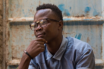 Thoughtful Young Black Man with Glasses in Blue Shirt