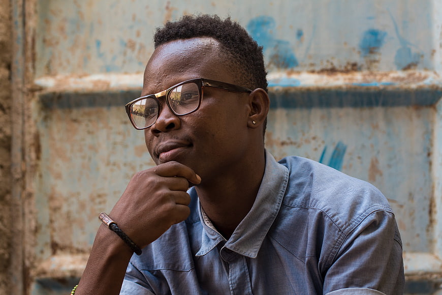 Thoughtful Young Black Man with Glasses in Blue Shirt