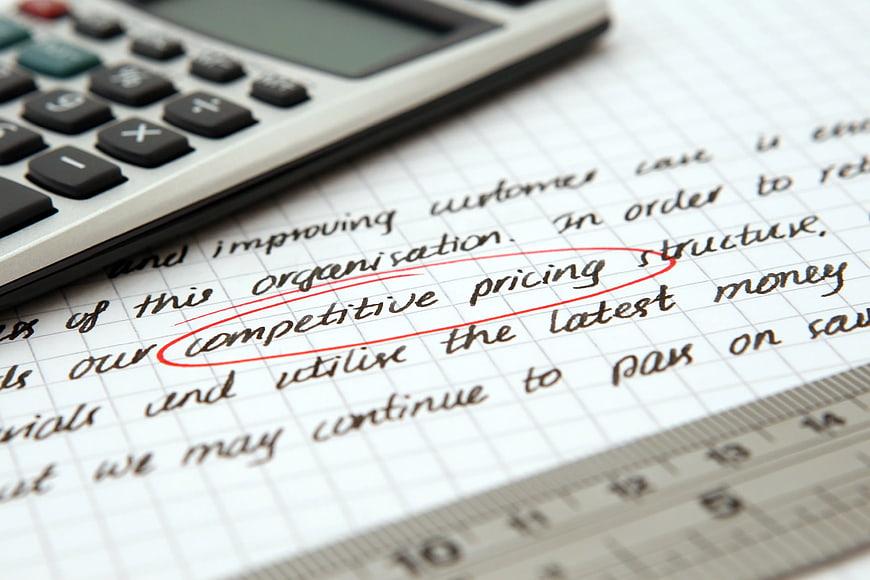 Competitive pricing handwritten text circled on paper with calculator