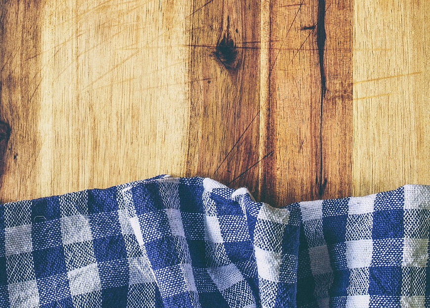 Blue and white checkered cloth on rustic wooden table background