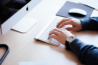 Hands Typing on White Keyboard at Modern Office Desk