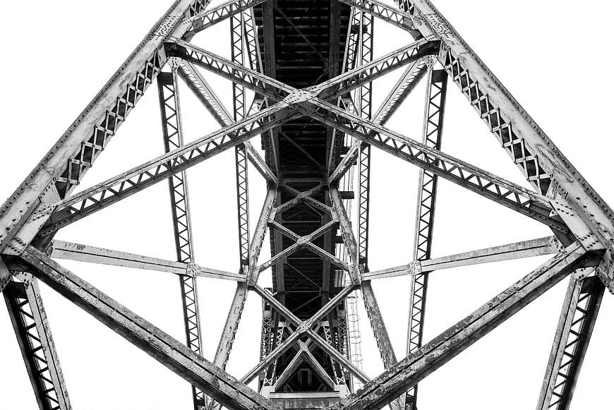 Black and white worm's eye view of steel bridge truss structure