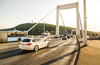White car driving on Budapest bridge with traffic