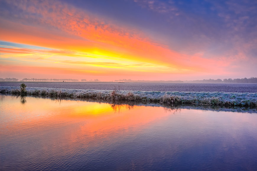 Vibrant Winter Sunrise Over Frosty Canal Landscape