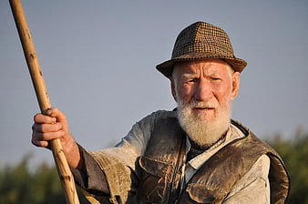 Portrait of elderly bearded man with hat and wooden staff