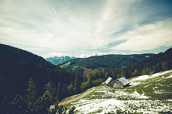Rustic wooden cabins in snowy mountain landscape with forest