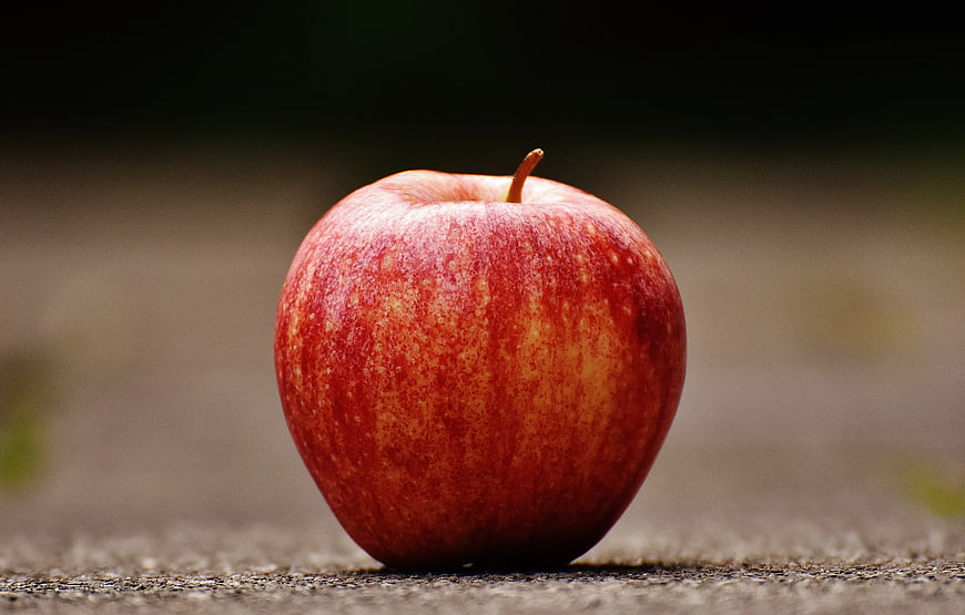 Close-up of Red Apple on Textured Pavement