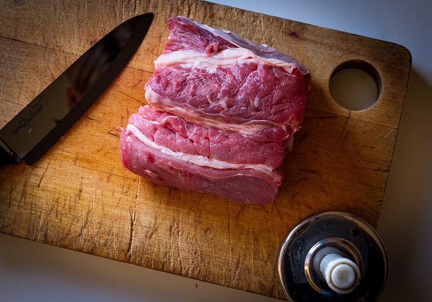 Raw Beef Roast on Wooden Cutting Board with Chef Knife