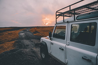 White off-road SUV parked on gravel road at sunset