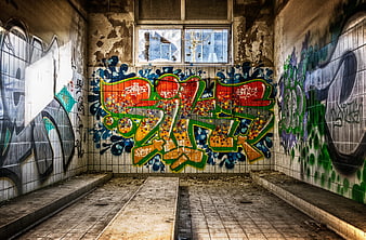 Abandoned tiled room with colorful graffiti and broken windows
