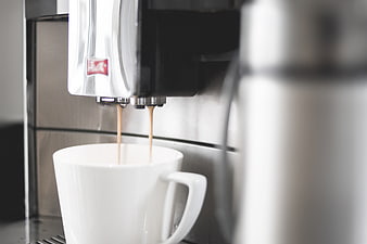 Espresso pouring into white cup from coffee machine