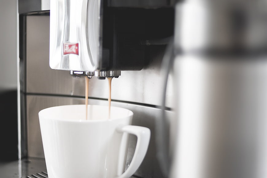Espresso pouring into white cup from coffee machine