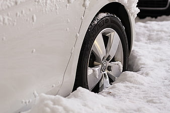White Volkswagen car wheel stuck in deep winter snow