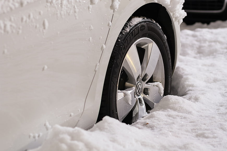 White Volkswagen car wheel stuck in deep winter snow