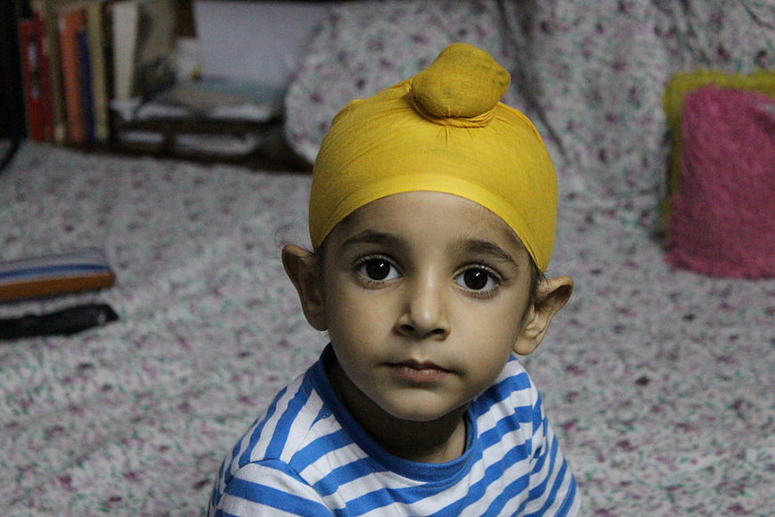 Portrait of a young boy wearing a yellow turban and striped shirt