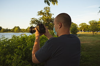 Man with Camera and Mask Photographing Lake in Park