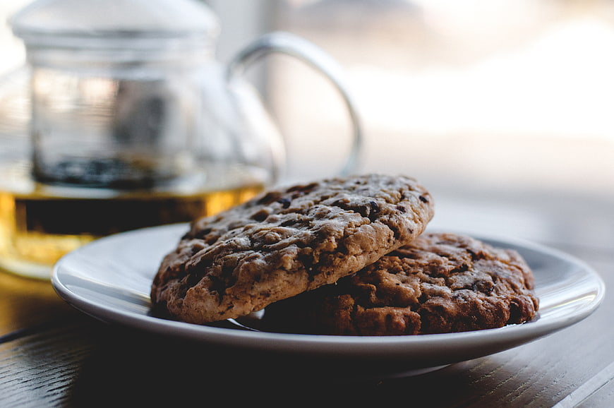 Homemade chocolate chip cookies on a white plate with tea
