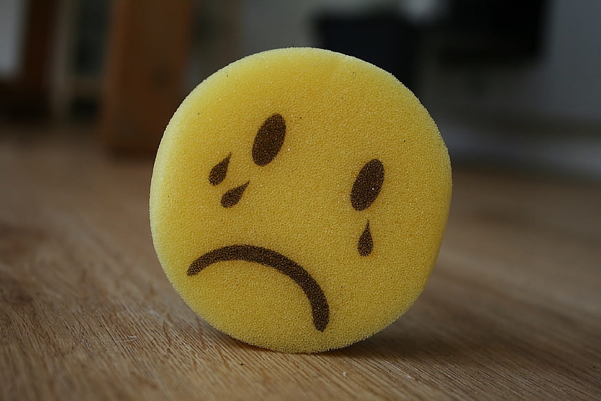 Sad Yellow Sponge Emoticon on Wooden Surface