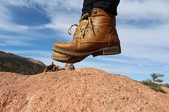 Hiking boots jumping on red rock with blue sky background