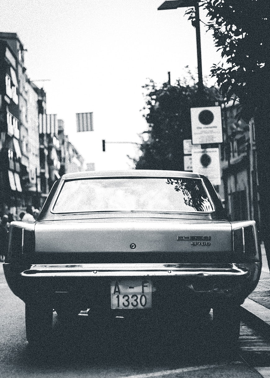 Vintage black and white photo of classic car rear on city street