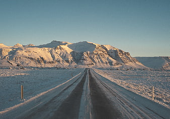 Snowy road leading to majestic winter mountain landscape