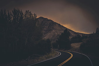 Winding Mountain Road at Dusk with Dramatic Sky