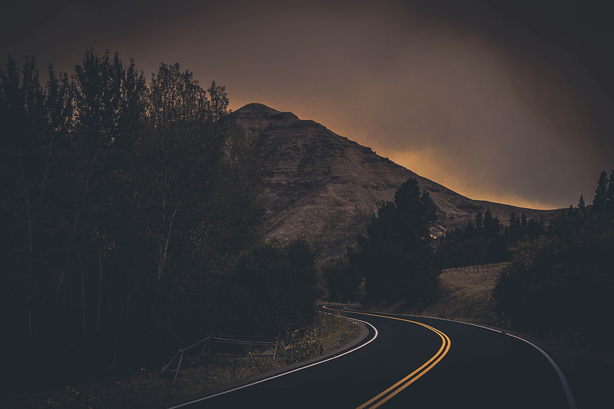 Winding Mountain Road at Dusk with Dramatic Sky