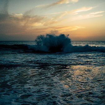 Dramatic Ocean Wave Crashing at Sunset with Golden Sky