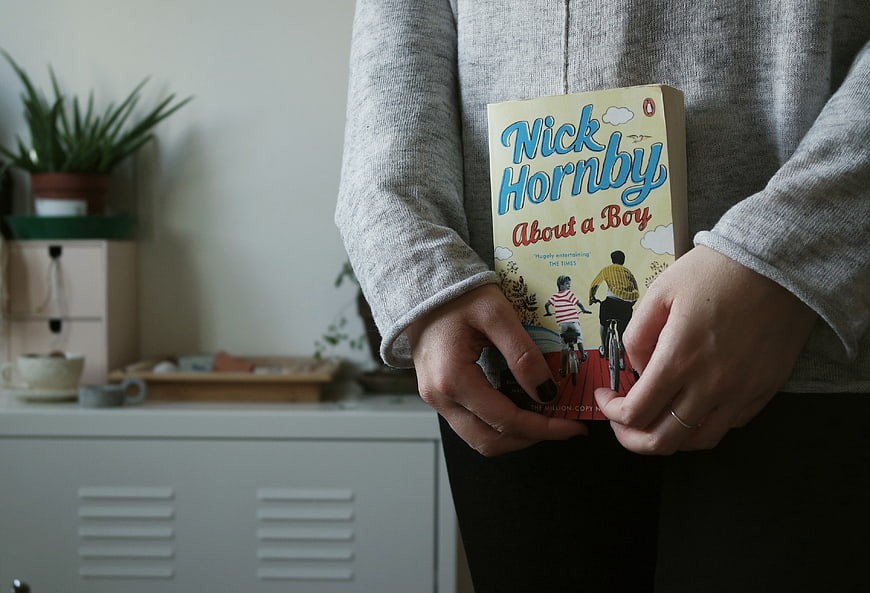Person holding Nick Hornby book About a Boy indoors