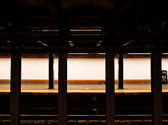 Empty subway station platform viewed through dark pillars