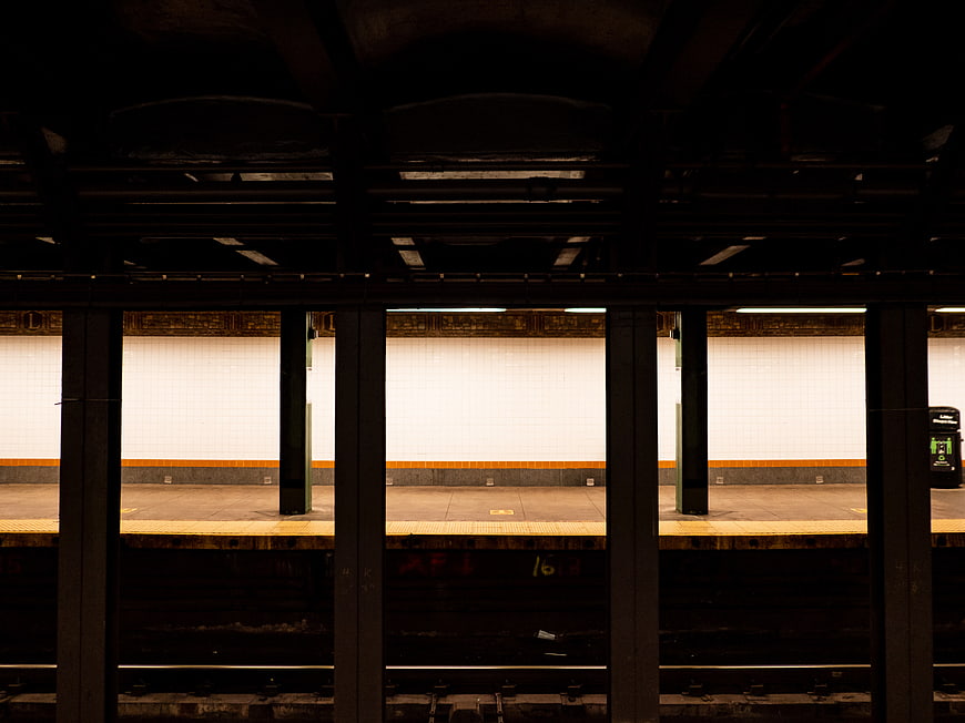 Empty subway station platform viewed through dark pillars