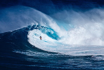 Surfer riding massive blue ocean wave barrel