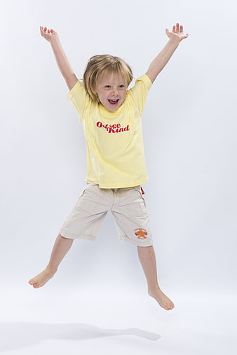 Happy young boy jumping in the air wearing a yellow t-shirt